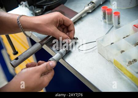 Les mains des hommes mesurent un micromètre de rondelles de compression spéciales pour régler les injecteurs de gazole Banque D'Images