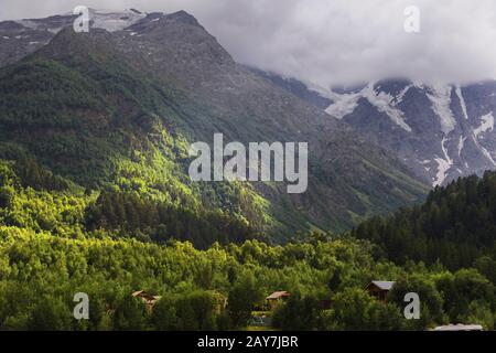 Paysage vertical, la lumière du soleil qui traverse les nuages illumine localement la section de pente au pied du caucasien Banque D'Images