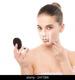 Jeune femme brune avec un visage propre appliquer le rouge à lèvres à l'aide d'un miroir. Isolé sur fond blanc. Banque D'Images