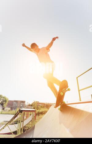 Skater pour adolescents accroché sur une rampe sur un skateboard dans un parc de skate Banque D'Images