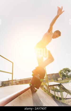 Skater pour adolescents accroché sur une rampe sur un skateboard dans un parc de skate Banque D'Images