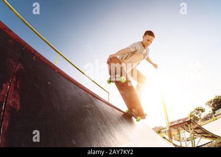 Skater pour adolescents accroché sur une rampe sur un skateboard dans un parc de skate Banque D'Images