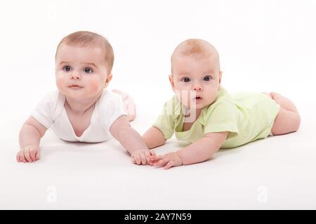 Bébé fille et garçon couché sur un fond blanc et holding hand Banque D'Images