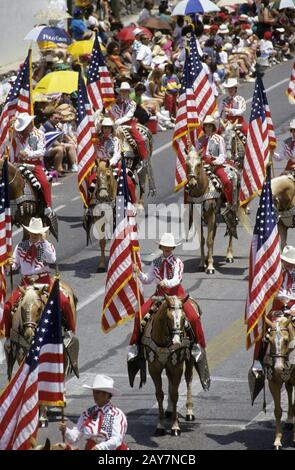 San Antonio, Texas : des cavaliers brandissant un drapeau américain participent au défilé de la bataille des fleurs, qui fait partie de la fête annuelle du printemps de San Antonio. ©Bob Daemmrich Banque D'Images