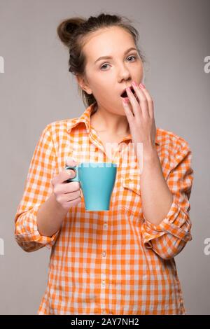 Studio portrait d'une femme endormie dans un T-shirt orange avec une tasse Banque D'Images