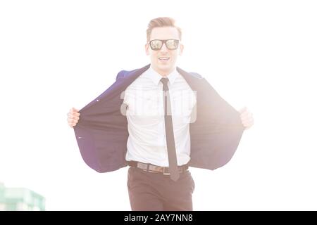 Joli petit butunessman en costume bleu et lunettes de soleil se tiennent o Banque D'Images