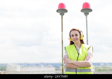 Jolie femme de travail dans le vert ouest et les couvre-oreilles se tiennent sur le toit, tenir la tablette Banque D'Images