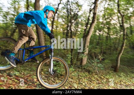 un jeune gars dans un casque vole atterri sur un vélo après avoir sauté d'un éjecteur Banque D'Images