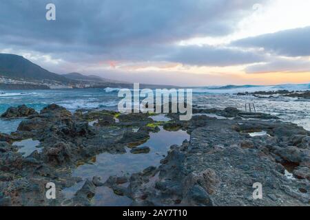 Plage de rochers de Punta del Hidalgo au coucher du soleil vue panoramique du village de Bajamar Banque D'Images