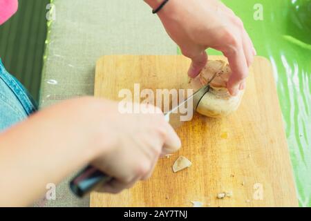 Mains féminines coupées en gros champignons en bois sur une planche à découper. Banque D'Images