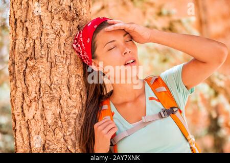 Femme de randonnée déshydratée fatiguée soif sentiment épuisé de coup de chaleur. Fille avec maux de tête de la température chaude sur activité extérieure randonneur style de vie. Banque D'Images