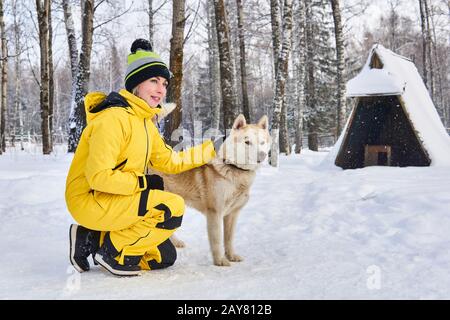 la jeune femme communique avec un chien husky dans la forêt hivernale Banque D'Images