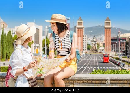 Deux heureux touristes regardant la carte en voyageant à Barcelone, près des tours vénitiennes et de la place de l'Espagne Banque D'Images