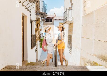 Deux filles touristiques admirant une vue superbe sur les pots de fleurs sur les murs blancs sur la célèbre rue Flower en Andalousie Banque D'Images