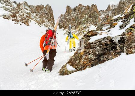 Les skieurs extrêmes grimpent au sommet le long du coulier entre les rochers avant la descente du freeride backcountry Banque D'Images