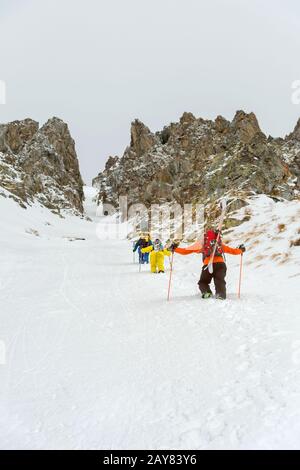 Les skieurs extrêmes grimpent au sommet le long du coulier entre les rochers avant la descente du freeride backcountry Banque D'Images