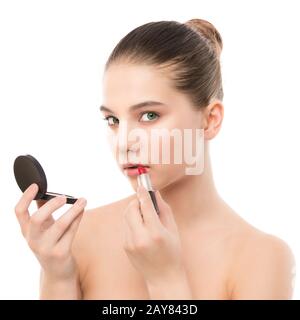 Jeune femme brune avec un visage propre appliquer le rouge à lèvres à l'aide d'un miroir. Isolé sur fond blanc. Banque D'Images