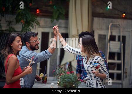 deux couples socialisant dans un café extérieur, plaisante, rire, haut cinq mains. socialisation, couples, multiethnique, amis, loisirs, wining, concept Banque D'Images