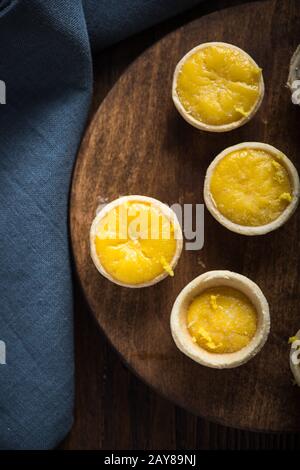 Mini tartes au citron et à la crème anglaise sur planche en bois Banque D'Images
