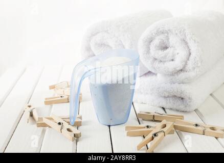 Serviettes de bain, poudre à laver dans la tasse à mesurer et des clous de girolettes en bois Banque D'Images