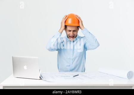 Ingénieur sérieux et sérieux, chargé de travailler sur un grand projet architectural en retard, assis dans son espace de travail à l'aide de l'onglet numérique Banque D'Images