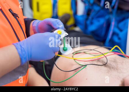 Médecin d'urgence, en joignant les mains les électrodes ECG à la poitrine du patient en ambulance Banque D'Images