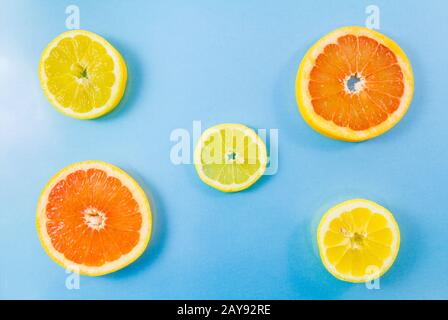 Deux tranches de pamplemousse et trois tranches de citron sur fond bleu. Banque D'Images