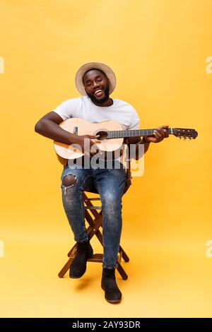 Photo de pleine longueur artistique excité homme jouant de la guitare. Isolé sur fond jaune. Banque D'Images