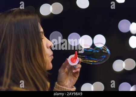 Femme ayant du plaisir à faire des bulles de savon à la fête de nuit ou à la fête de la veille de nouvel an Banque D'Images