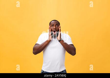 Un jeune taille afro-américaine surbahé portant un t-shirt blanc tenant les mains dans un geste surprise, en gardant la bouche bien ouverte, regardant Banque D'Images