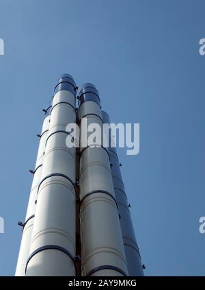 un groupe de grands cheminées industrielles en acier moderne, debout contre un ciel bleu vif Banque D'Images