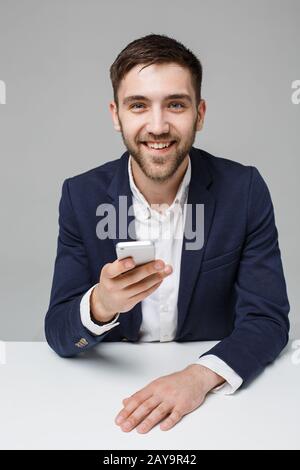 Concept d'affaires - Portrait beau heureux beau homme d'affaires en costume jouer à la moblie téléphone et sourire avec ordinateur portable au travail de Banque D'Images