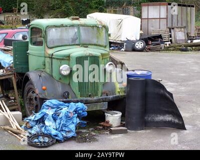 un vieux camion vert rouillé avec du bois de ferraille et du métal dans un jardin rural en junkyard Banque D'Images