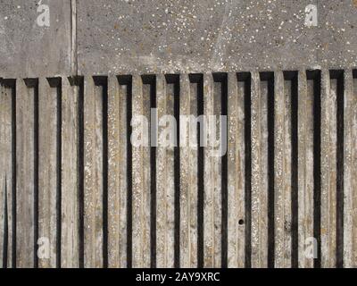ancien mur extérieur en béton avec rayures verticales cannelées et texture rugueuse en fonte avec ombre Banque D'Images