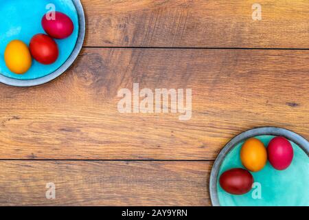 Six œufs de Pâques colorés sur deux assiettes avec fond en bois Banque D'Images