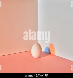 Oeufs colorés avec un reflet bleu-orange de l'ombre autour d'un double-fond gris-beige avec copie espace. Concept de Pâques. Banque D'Images