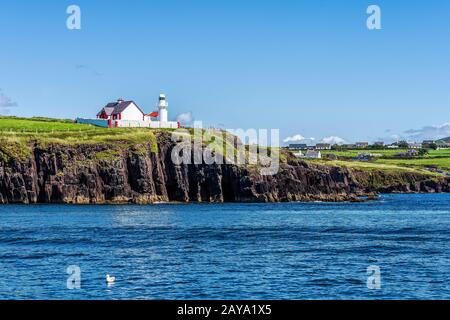 Phare sur la falaise avec village à une distance Banque D'Images