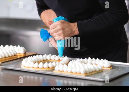 Vue en gros, les mains du chef avec la préparation d'une crème sac confiserie fiftie ans cake pâtisserie cuisine. Banque D'Images