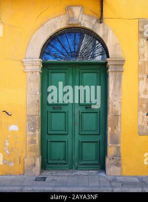 ancienne porte double verte dans un cadre en pierre dans un mur peint en jaune typique du style de l'ancien bâtiment Banque D'Images