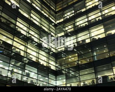 fenêtres illuminées illuminées dans un grand bâtiment de bureau géométrique moderne la nuit avec des espaces de travail Banque D'Images