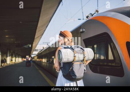 Transport thématique et voyage. Jeune femme caucasienne debout à la plate-forme de la gare près du train arrière train arrière fond avec Banque D'Images