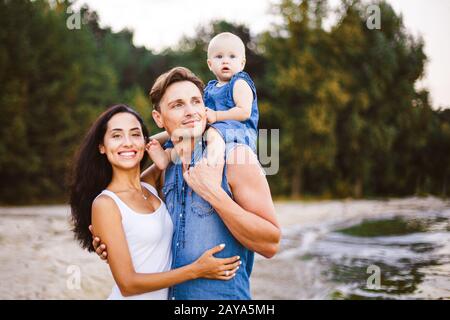 belle jeune famille en vacances avec bébé. Le père tient la blonde dans ses bras, et la mère de la brunette la hante Banque D'Images