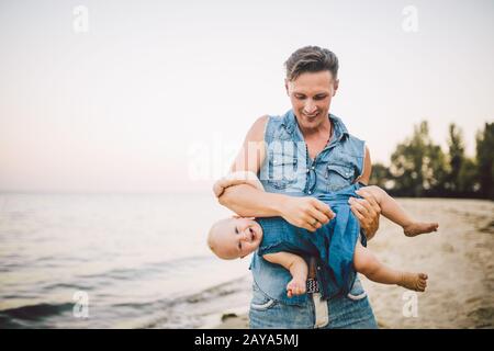 Thème paternité et repos avec un enfant en mer. Le jeune beau père caucasien joue aime jeter dans les bras son enfant Banque D'Images
