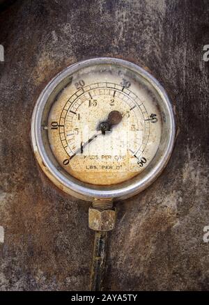 Ancien manomètre industriel rond rouillé avec chiffres autour du cadran monté sur une surface métallique de Banque D'Images