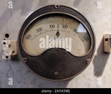 un grand ampèremètre industriel rond vintage avec cadran analogique avec numéros avec symboles électriques standard sur cadran blanc activé Banque D'Images