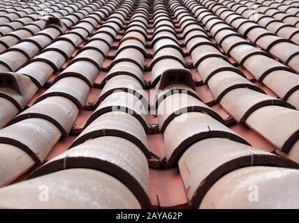 vue de perspective décroissante plein cadre d'un vieux toit avec tuiles rouges argileuses incurvées dans des lignes avec fentes de ventilation Banque D'Images