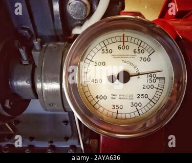 un grand compte-tours en métal ancien avec une jauge ronde avec le cadran marqué dans les numéros montés sur un grand moteur Banque D'Images