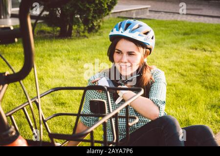 Cycliste féminin dans des vêtements de cyclisme professionnels et casque assis près du vélo, en profitant du soleil. Détente et repos. Une vie saine Banque D'Images