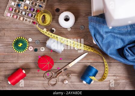 Couturière ou toile de fond avec jeans, outils à coudre, fils colorés, machine à coudre et accessoires . Banque D'Images