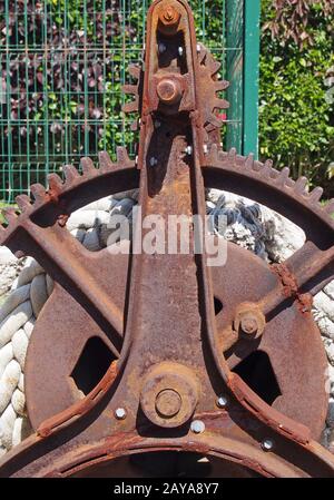 un vieux treuil en fer rouillé disutilisé avec des engrenages de roue à crémaillère cassés et une corde Banque D'Images